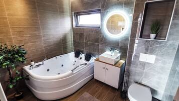 Un bagno moderno con una vasca da bagno freestanding, un mobile lavabo con specchio e un water.