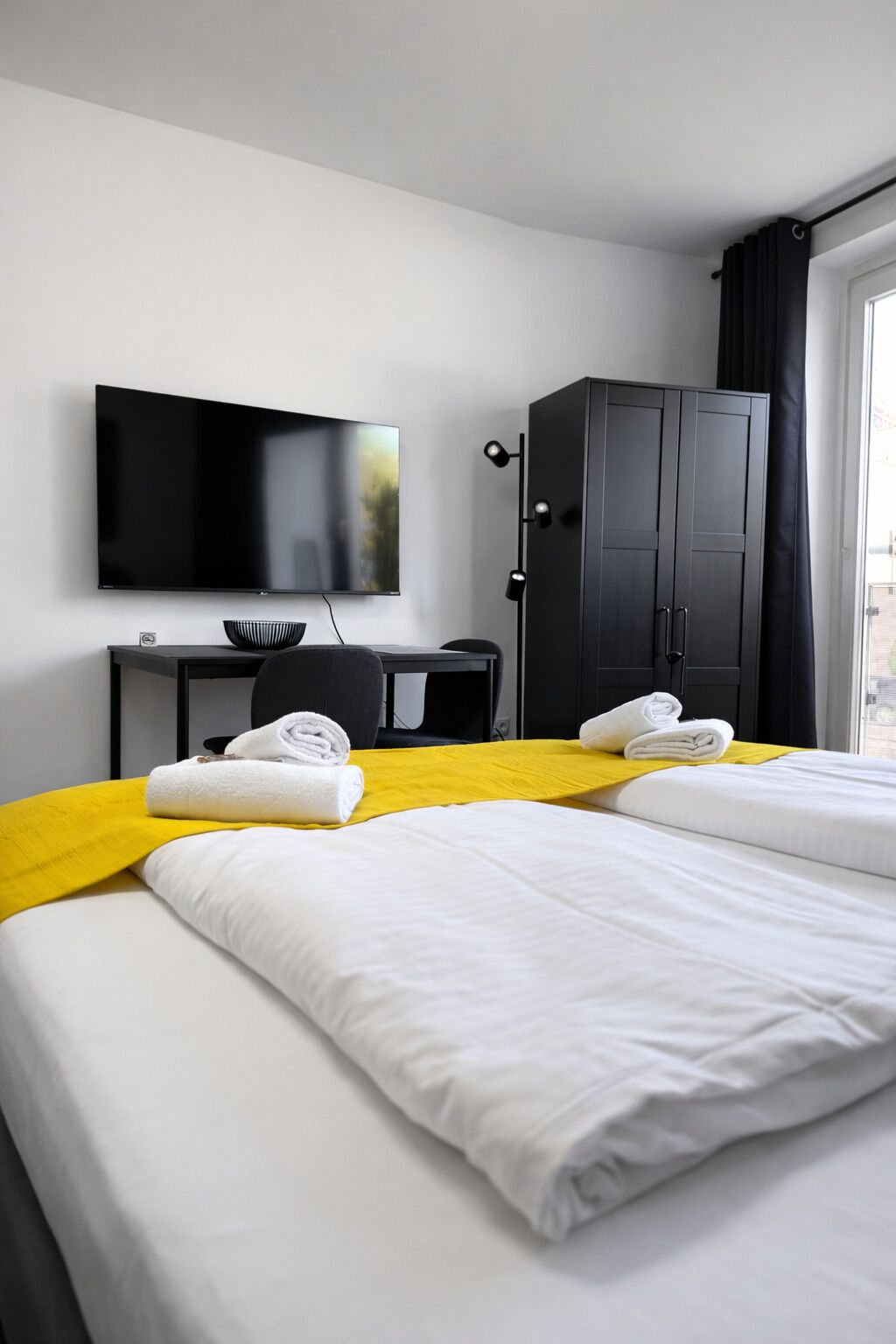 Une chambre d’hôtel avec deux lits, un bureau, une télévision et une armoire.