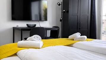 Une chambre d’hôtel avec deux lits, un bureau, une télévision et une armoire.