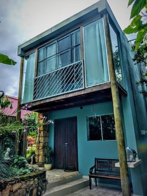 A two-story house with a balcony, a front door, and a small garden area. - Pousada Zazen (Palmeiras)