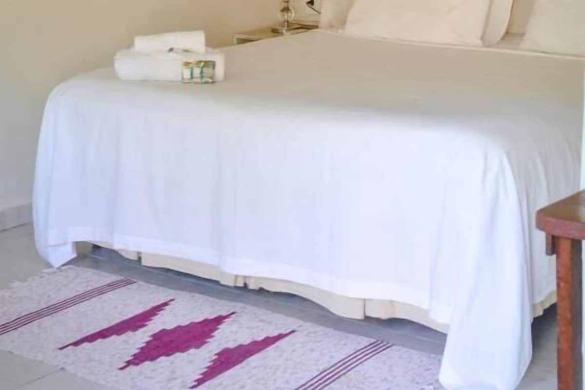Quarto com cama, mesa de cabeceira, abajur e dossel.