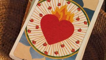 A single tarot card with a heart and flame design, placed on a woven basket.