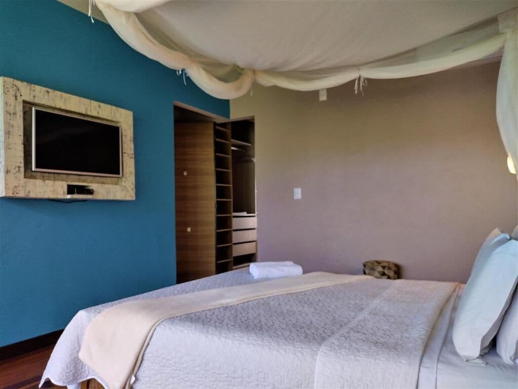 Quarto com cama, televisão na parede e guarda-roupa.