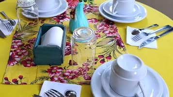 A table set with white dishes, silverware, and a floral tablecloth.