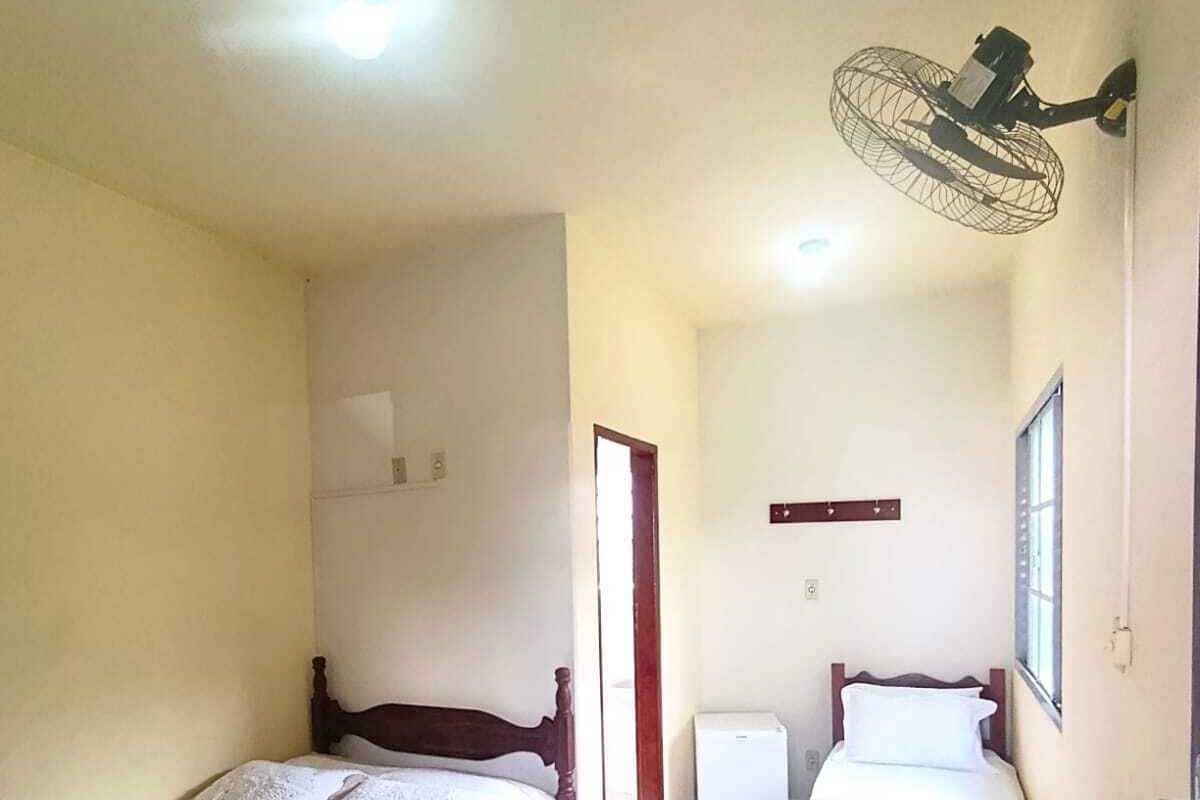 Una habitación de hotel con dos camas, un escritorio, un ventilador y una ventana.