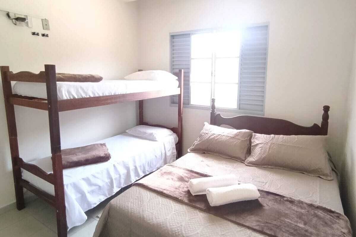 Una habitación con literas, una ventana con persianas y una pequeña mesa.