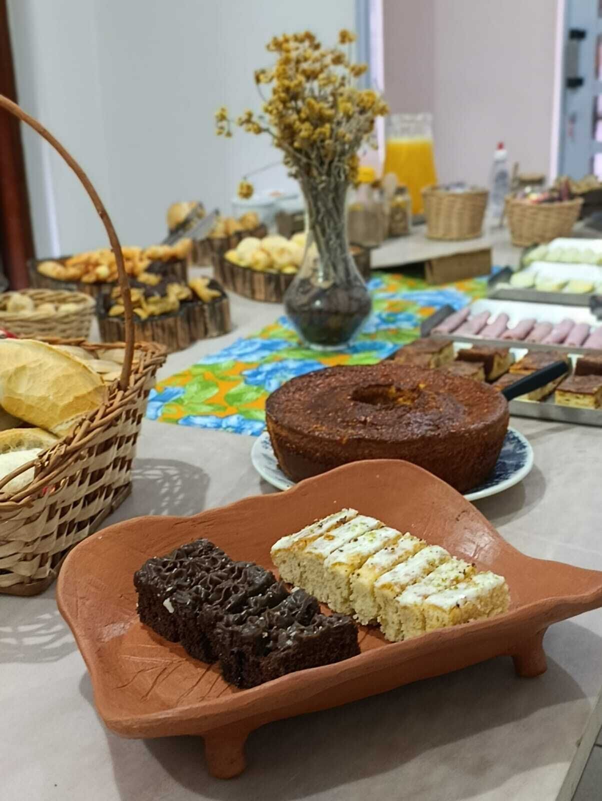 A table with various baked goods, including a cake and pastries, and a vase with dried flowers.