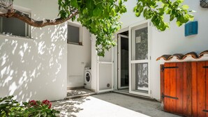 A residential property with a washing machine, a wooden gate, and a tree providing shade. - Apartment 'Casa Nenna' with Air Conditioning (San Vito)