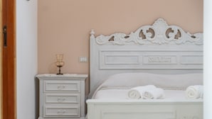 A bedroom with a white bed, a nightstand with a lamp, and a door to the left. - Apartment 'Casa Nenna' with Air Conditioning (San Vito)