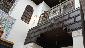 A traditional interior with ornate wooden paneling, a patterned tile wall, and a hanging light fixture. - Riad Symphony 808 (Fes)