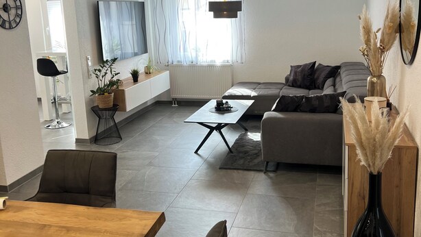 A modern living room with a sofa, coffee table, and dining area. - Andy's apartment (Malsch)