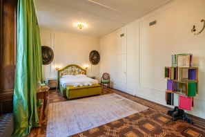 Ein Schlafzimmer mit Bett, Sessel, Nachttisch, Spiegel und einer Dekorecke.
