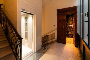 A staircase with a metal railing, a wooden door with a decorative panel, and a tiled floor. - Noble and imperial residence Catullus (Verona)