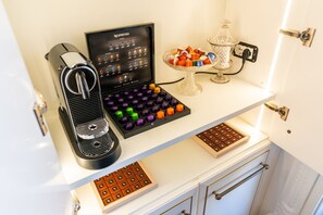 A coffee machine, a chocolate board, and a glass dish with chocolates on a white countertop. - Noble and imperial residence Catullus (Verona)