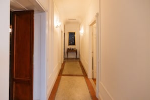 A hallway with a wooden door, a rug, a small table with items, and a painting on the wall. - Noble and imperial residence Catullus (Verona)
