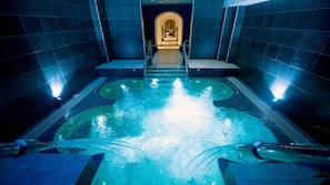 A hot tub with a central fountain, surrounded by tiled walls and a tiled floor.