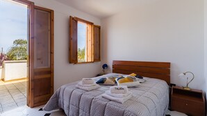 Una camera da letto con un letto, due porte aperte, un comodino e una finestra.