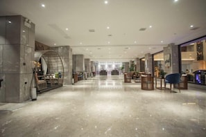 A spacious lobby with a marble floor, seating areas, and a reception desk. - Qixinlong Sightseeing Hotel (Zhenyuan County)