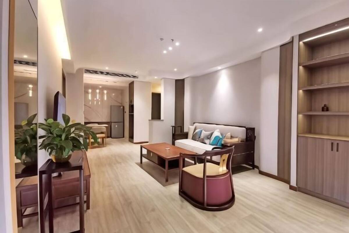 A modern living room with a sofa, coffee table, and dining area. There is a kitchen in the background.