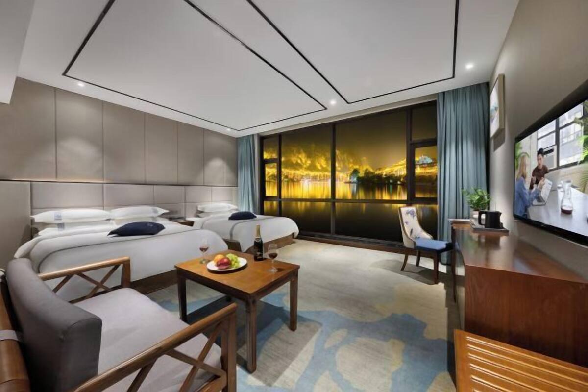 A modern hotel room with a large bed, a desk, a chair, and a TV.
