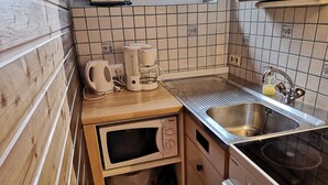 Eine kleine Küche mit Mikrowelle, Kaffeemaschine und Spüle.