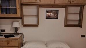 Ein Schlafzimmer mit einem Bett, Holzschränken, einem Schreibtisch und einer Lampe.