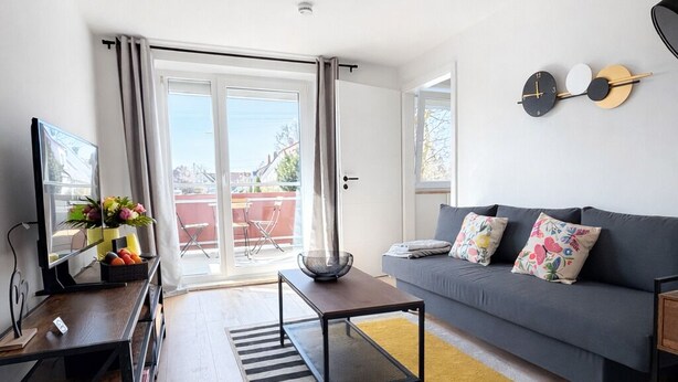 Ein modernes Wohnzimmer mit Sofa, Couchtisch und einer Wanduhr.