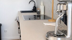 Eine moderne Küche mit einer Edelstahl-Espressomaschine, einem schwarzen Wasserhahn und einer Marmor-Spritzschutzwand.