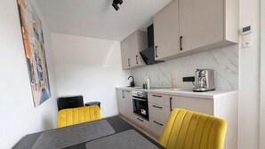 Eine kompakte Küche mit modernen Geräten, ein Essbereich mit Tisch und Stühlen sowie ein einzelnes Kunstwerk an der Wand.