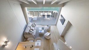 A modern interior with a dining area, sofa, and a balcony with outdoor seating. - Palazzo Cordigero (Peschiera del Garda)