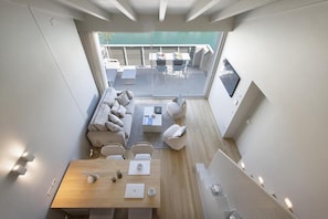 Un intérieur moderne comprenant un coin repas, un canapé et un balcon avec des sièges d’extérieur.
