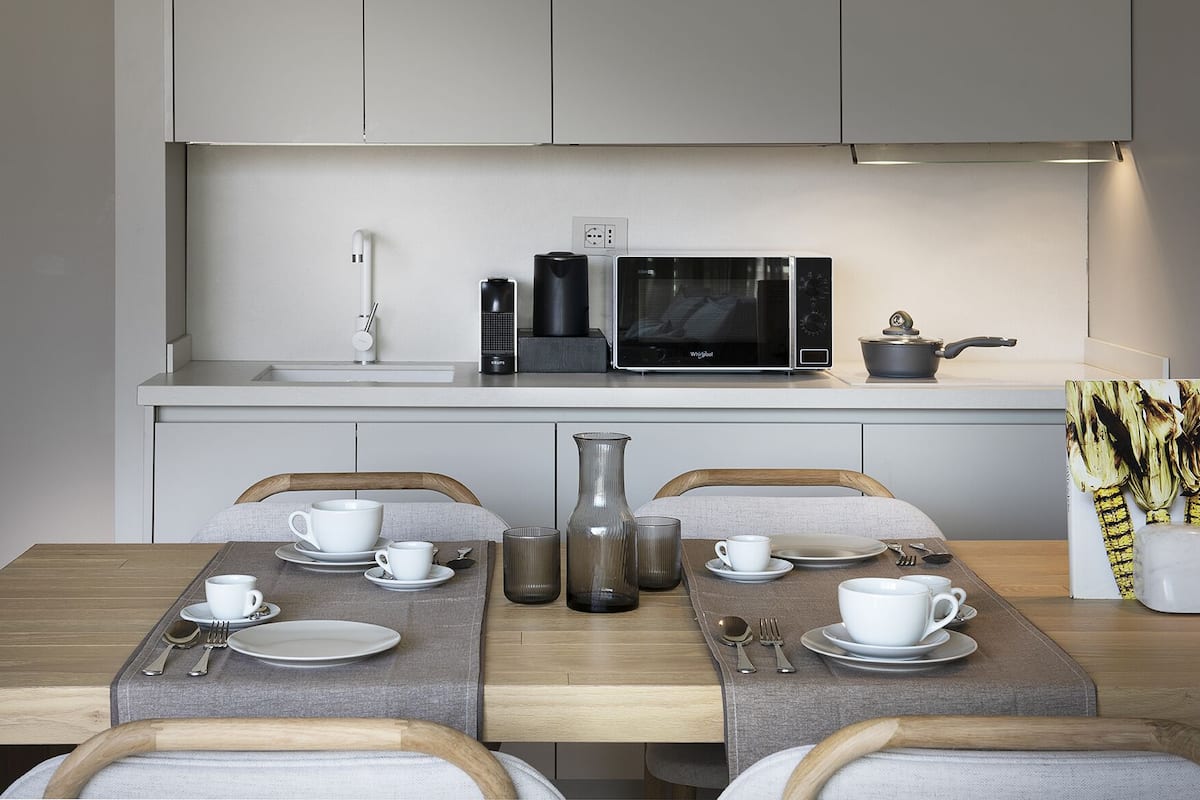 A modern kitchen with a microwave, coffee maker, and kettle on the countertop.