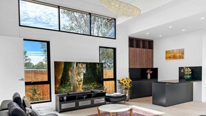 Een moderne woonkamer met een grote flatscreen televisie, zwarte leren banken, een ronde salontafel en een decoratief vloerkleed.