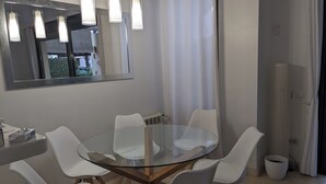 A modern dining area with a glass table surrounded by white chairs, a mirror above the table, and pendant lights. - 3-bedroom villa in peaceful  Roda Golf with AC (San Javier)