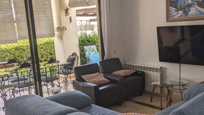 A living room with a grey sofa, a TV, and a painting on the wall. - 3-bedroom villa in peaceful  Roda Golf with AC (San Javier)