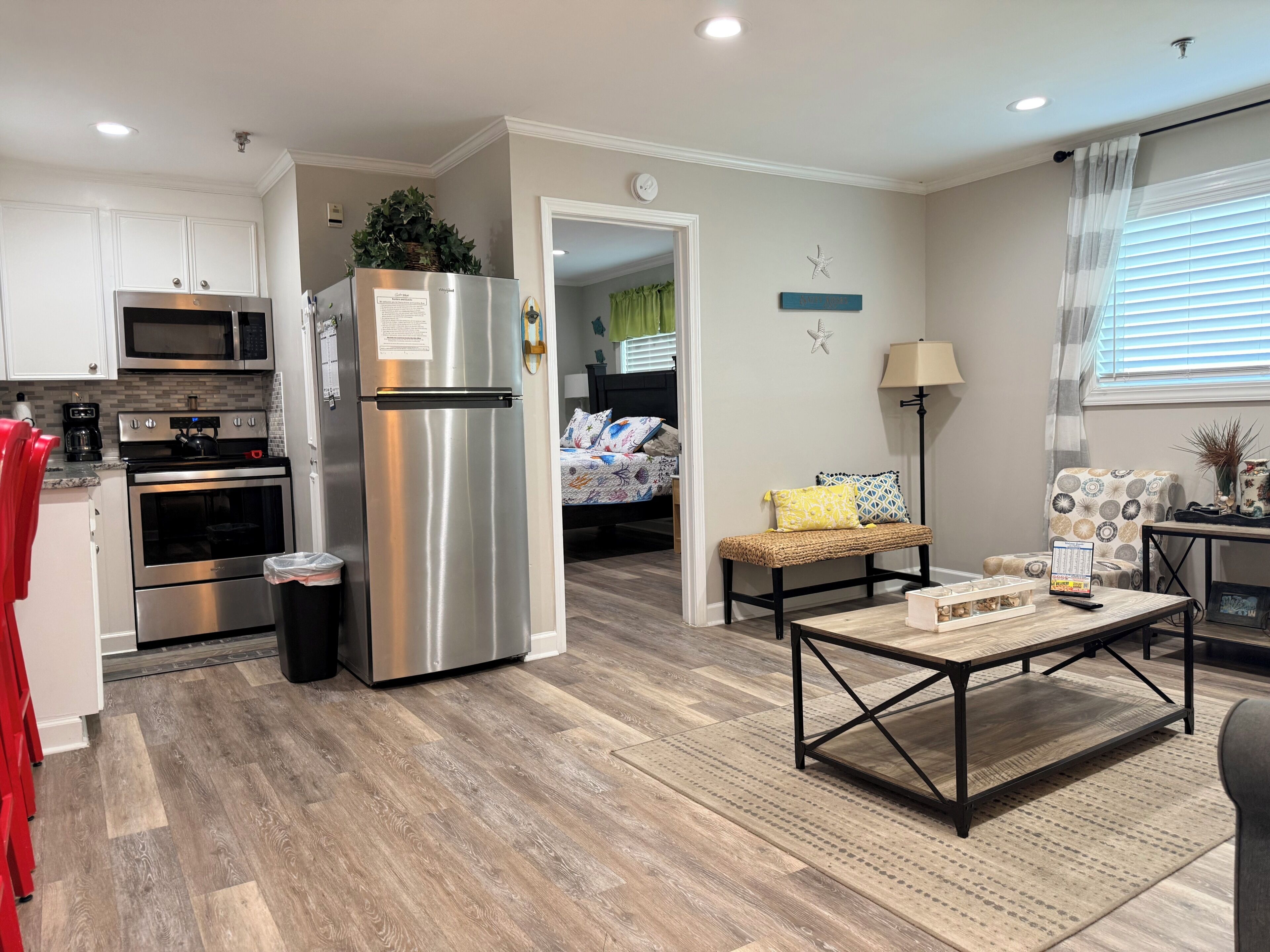 Une cuisine moderne dotée d’appareils électroménagers en acier inoxydable, un coin repas avec une table en bois et un espace salon confortable avec un banc.