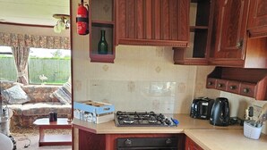 Uma cozinha compacta com armários de madeira, fogão a gás, cafeteira e forno pequeno.