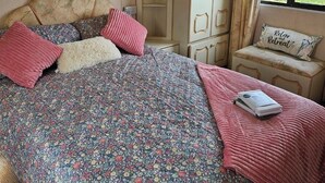 Quarto com cama grande, mesa de cabeceira, cadeira, guarda-roupa e janela com vista.