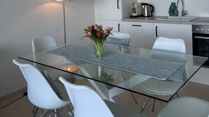 Eine moderne Küche mit weißen Schränken, einem Glastisch und weißen Stühlen.