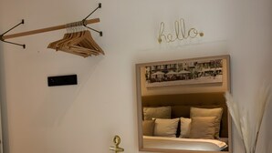 Ein Schlafzimmer mit einem Bett, einem Nachttisch mit Spiegel, einer Hängelampe, einer Wandheizung und einem Schild mit dem Aufdruck 'hello'.