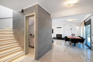 A modern interior with a staircase, a dining area, and a kitchen visible through an open doorway. - Rhodes Villa Billys in Sgourou (Rhodes)
