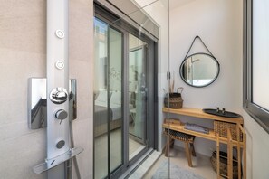 Ein modernes Badezimmer mit Duschabtrennung aus Glas, einem Holzwaschtisch mit Körben und einem runden Spiegel an der Wand.