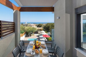 Ein Balkon mit Frühstückstisch, Blick auf einen Pool und die malerische Seelandschaft.