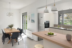 Eine moderne Küche mit Holztisch, schwarzen Stühlen und einer zentralen Kochinsel mit einer Vase.