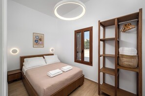 Une chambre à coucher bien rangée, avec un lit, des tables de chevet, une armoire et un tableau encadré au mur.