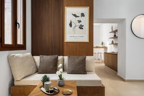 A modern living room with a sofa, a coffee table, and a framed botanical print on the wall. - Aroha Apartment 1 in Rhodes Old Town (Old Town Rhodes)
