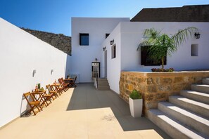 Un bâtiment moderne avec une façade blanche, un mur en pierre et un escalier menant à l’entrée.
