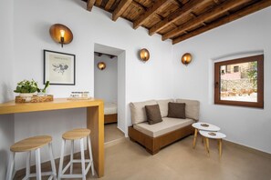 Ein modernes Wohnzimmer mit Holzboden, einer Couch, einem kleinen Tisch und einer Bar mit Hockern.