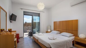 A modern bedroom with a large bed, a wooden headboard, a TV mounted on the wall, and a balcony with a stone wall. - High View Villa in Afantou (Rhodes)