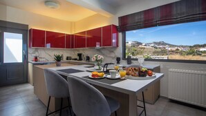 A modern kitchen with a central island, red cabinets, and a view of the landscape. - High View Villa in Afantou (Rhodes)